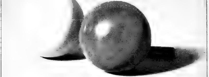 Cross's photograph of two polished spheres under one light, a white one at the left, partly behind the red one, its lit side lost against the white ground so that mainly its shadow side and cast shadow show, and a red one in front with a bright side, a shadow side and a cast shadow; a stick of charcoal lies in the red sphere's shadow.