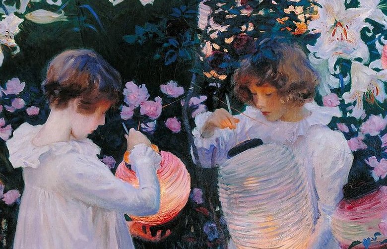 Detail of two girls in white dresses lighting paper lanterns among lilies at dusk; the left lantern glows orange-pink, and the pale one in front of the girl at right lights her face from below.
